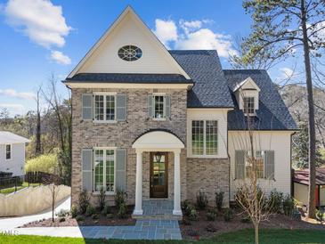 Charming two-story brick home featuring gray shutters, a covered entry, and manicured landscaping at 126 E Drewry Ln, Raleigh, NC 27609