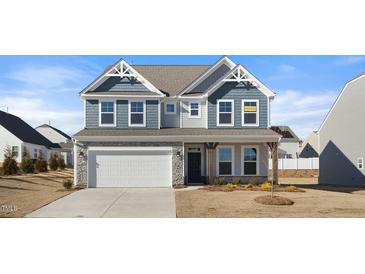 Two-story home with gray siding, stone accents, and a three-car garage at 1078 Gibson House Dr, Burlington, NC 27215