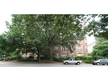 Brick apartment building featuring large shade trees, street view, and visible tenant parking at 1001 Hillsborough St # 304, Raleigh, NC 27603