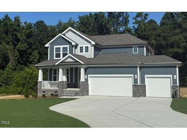 Inviting home featuring a two-car garage, covered porch, stone accents, and well-manicured lawn at 236 Alden Way, Angier, NC 27501