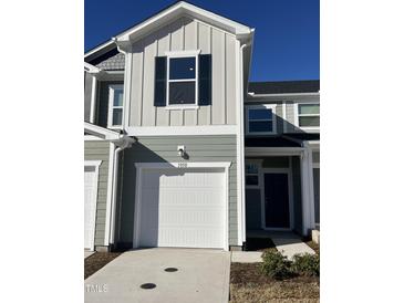 Charming exterior of a two-story home featuring a white garage door, light green siding and black shutters at 1050 Mountain Crown St, Durham, NC 27703