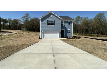 Charming two-story home with a garage and a long driveway on a sunny day at 259 Johnson Ridge Way, Four Oaks, NC 27524