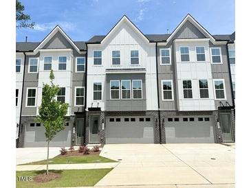 Modern townhome exterior features a two-car garage and a well-maintained lawn at 2007 Opulent Oaks Ln # 24, Durham, NC 27713