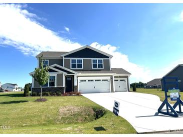 Two-story home featuring a three-car garage, well-manicured lawn, and a charming dark grey and beige exterior at 224 Bering Cir, Angier, NC 27501