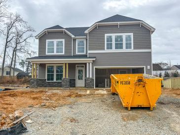 New two-story home featuring gray siding, stone accents, a two-car garage, and a covered porch in a construction phase at 105 Blackmon Ridge Ct # 15, Fuquay Varina, NC 27526