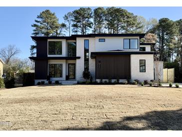 Striking two-story modern home with a white brick facade and contrasting dark wood accents at 662 Manchester Dr, Raleigh, NC 27609