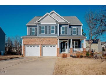 Two-story home with brick and siding exterior, two-car garage, and front porch at 454 Big Willow Way, Rolesville, NC 27571