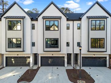 Modern townhomes feature a light neutral palette with dark trim, black garages, and landscaped front yards at 811 Maple Berry Ln # 102, Raleigh, NC 27607