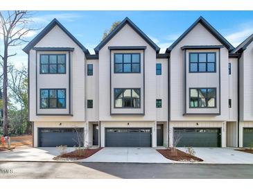 Modern townhomes boast a crisp white exterior, dark trim, and attached garages for convenient parking at 811 Maple Berry Ln # 105, Raleigh, NC 27607
