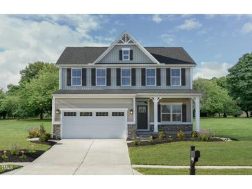 Charming two-story home with a covered front porch, attached garage, and beautifully landscaped front yard at 8841 Tartan Clan Dr, Willow Springs, NC 27592