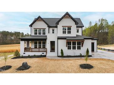 New construction home with white brick, black trim, covered porch and tasteful landscaping at 55 Firefly Ln, Louisburg, NC 27549