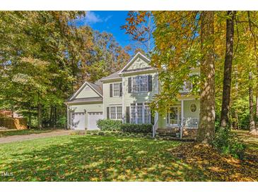 Two-story home with a two-car garage, lush green lawn, and mature trees, set under a sunny blue sky at 413 Chadwick Ln, Efland, NC 27243