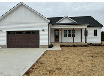 Charming new construction exterior featuring a covered porch and a two-car garage at 8536 Savage Rd, Spring Hope, NC 27882