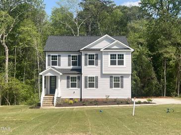 Charming two-story home with gray siding, a covered entryway, manicured landscaping, and a lush green lawn at 266 Fast Pitch Ln, Four Oaks, NC 27524