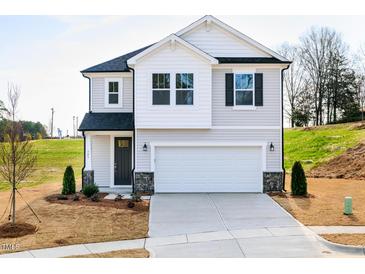 Charming two-story home featuring a 2-car garage, manicured lawn, and stylish black and white accents at 305 Little Creek Dr, Lillington, NC 27546