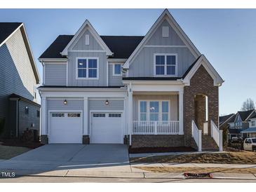 Two-story home featuring a two car garage, brick accents, and a covered front porch at 100 Mossy Falls Way, Wendell, NC 27591