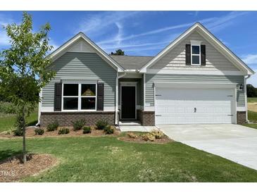 Charming single-story home featuring a manicured lawn, two-car garage, and inviting craftsman-style facade at 346 Olivia Crossing Ct # 12, Four Oaks, NC 27524