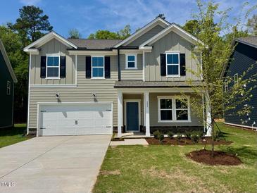 Charming two-story home featuring a two-car garage, blue front door, and a well-maintained landscaped front yard at 553 Fosterton Cottage Way, Raleigh, NC 27603