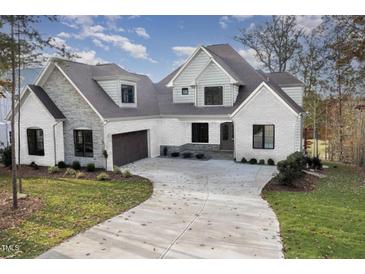Beautiful two-story home with a brick and stone exterior and a curved driveway at 736 Golfers View Vw, Pittsboro, NC 27312