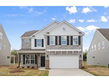 Charming two-story home featuring a stone facade, black shutters, and a two-car garage at 1228 Cricket St, Elon, NC 27244