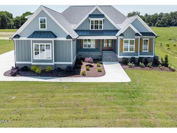 Charming exterior elevation with blue siding, manicured lawn, and inviting walkway at 70 Water Willow Ln, Zebulon, NC 27597