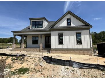 New construction home featuring vertical siding, brick foundation, covered porch, and black window frames at 5124 Grist Stone Way, Youngsville, NC 27596