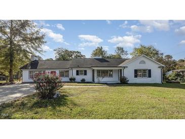 Charming single-story home with a well-maintained lawn, mature trees, and a classic white facade at 203 W Stewart St, Coats, NC 27521