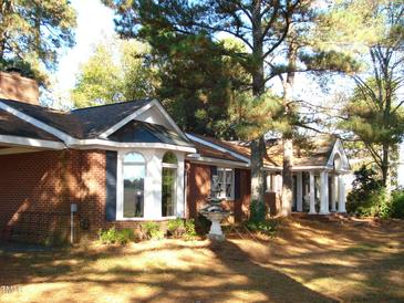 Charming brick home featuring arched windows and a welcoming entrance with elegant white pillars, creating a classic curb appeal at 6349 Elevation Rd, Benson, NC 27504