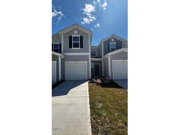 Charming townhome showcasing a well-manicured lawn and attached one car garage at 1103 Mountain Crown St, Durham, NC 27703