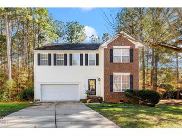 Charming two-story home featuring a brick accent, white siding, black shutters, and an attached two-car garage at 104 Full Moon Ct, Garner, NC 27529