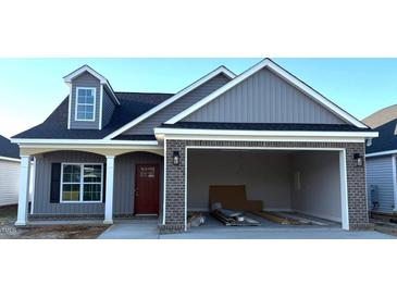 Charming home with gray siding, a brick-accented garage, and a welcoming red front door at 180 Brunswick Dr, Nashville, NC 27856