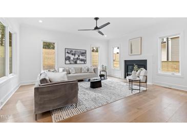 Bright living room featuring a modern fireplace, neutral decor, and hardwood flooring at 2417 Mayview Rd, Raleigh, NC 27607