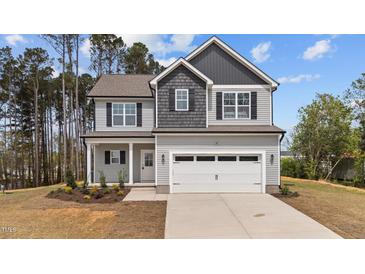Charming two-story home featuring a two-car garage, landscaped yard, and inviting covered porch at 60 Bennett Rd, Coats, NC 27521