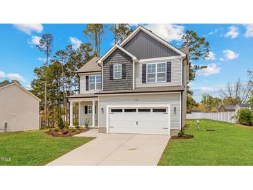 Charming two-story home with a well-manicured lawn, a two-car garage, and a mix of gray and light gray siding at 60 Bennett Rd, Coats, NC 27521