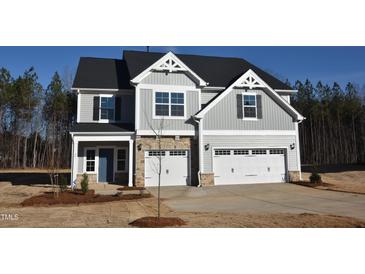 Beautiful two-story home with stone accents, gray siding, attached two-car garage, and professionally landscaped yard at 55 Accord Dr, Youngsville, NC 27596