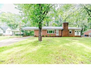 Charming brick home with well-kept lawn, carport, and a brick chimney, nestled among mature trees at 710 Spring Ln, Sanford, NC 27330