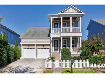 Charming home boasts a two-story porch, three-car garage, and a white picket fence at 1509 Heritage Reserve Ct, Wake Forest, NC 27587