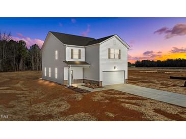 Two-story home with vinyl siding, attached garage, and new landscaping under a colorful sunset at 9154 Phoenix Ct, Middlesex, NC 27557