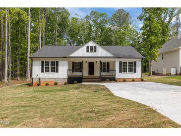 Charming single-story home with a welcoming front porch, black shutters, and manicured lawn at 200 Rawhide Dr, Louisburg, NC 27549