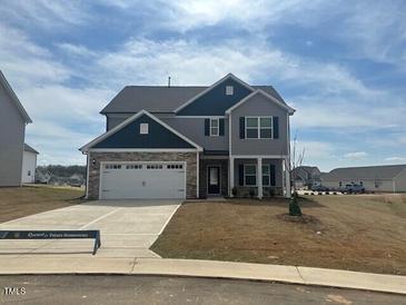 Two-story home featuring a gray exterior, stone accents, and a two-car garage on a landscaped lot at 105 Wilderness Ct, Mebane, NC 27302