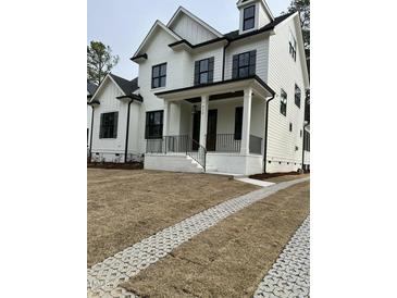 Stunning new construction featuring a painted brick facade, black window frames and a covered front porch at 314 Hinton St, Apex, NC 27502