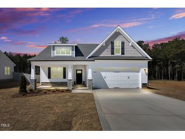 Beautiful single-Gathering home with a large two-car garage and covered front porch under a colorful sky at 91 Laramie Ln, Selma, NC 27576