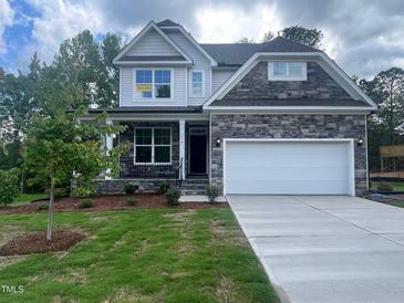 Beautiful two-story home featuring a stone facade, a two-car garage, landscaped yard, and a covered front porch at 116 Arundel Dr, Archer Lodge, NC 27527
