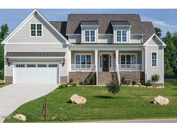 Inviting home featuring a manicured lawn, covered porch, brick accents and a white garage door at 1233 Azalea Garden Cir, Raleigh, NC 27603