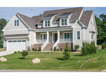 Charming two-story home with a covered porch, brick accents, and a well-manicured lawn at 1233 Azalea Garden Cir, Raleigh, NC 27603