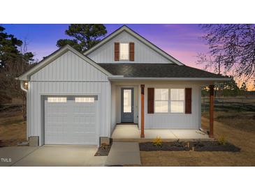 Charming white home with a gray door, wooden pillars and shutters against a colorful sunset sky at 5093 Nc 56 Hwy, Franklinton, NC 27525