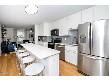 Modern kitchen features stainless steel appliances, white cabinets, and a breakfast bar that opens into the living area at 1320 S State Street # D, Raleigh, NC 27610