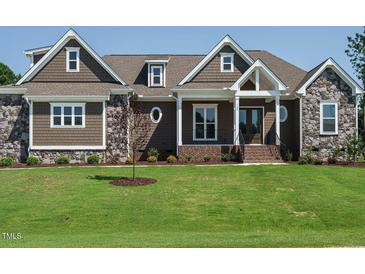 Charming home featuring stone accents, shingle siding, and a well-manicured lawn at 142 Batten Hill Ln, Selma, NC 27576