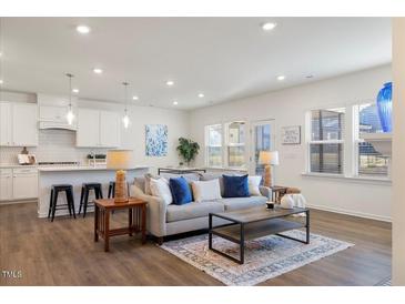 Bright living room featuring an open floor plan with modern furnishings and an adjacent kitchen area at 504 Morning Glade St, Wake Forest, NC 27587