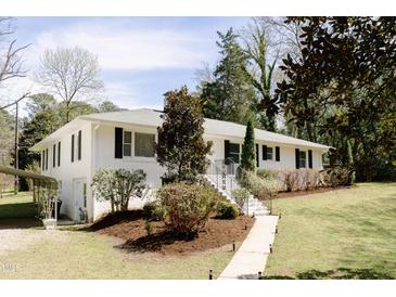 Charming white house with black shutters, landscaped front yard, and stone walkway leading to the front door at 42 Oakwood Dr, Chapel Hill, NC 27517